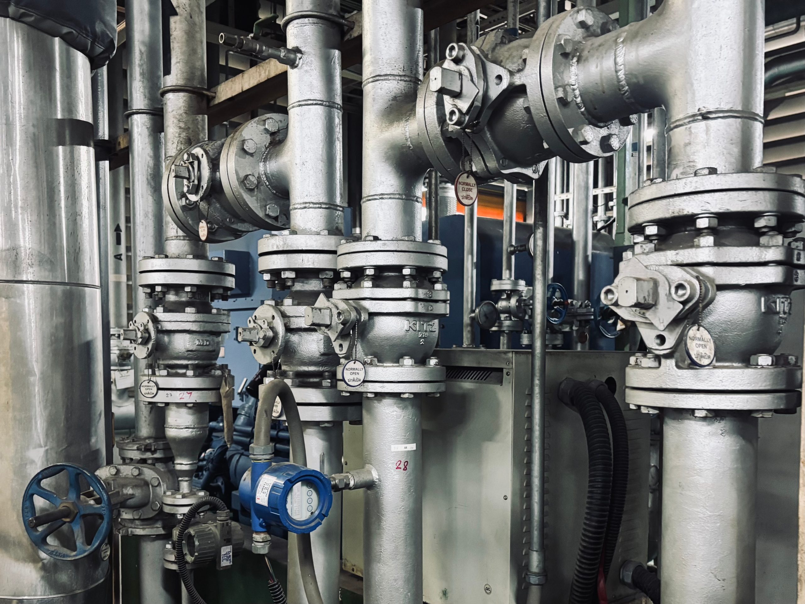 Old rusty industrial valves and metal pipes with peeling paint and corrosion, showcasing aged mechanical components in a vintage utility room. Close-up shot with natural lighting.